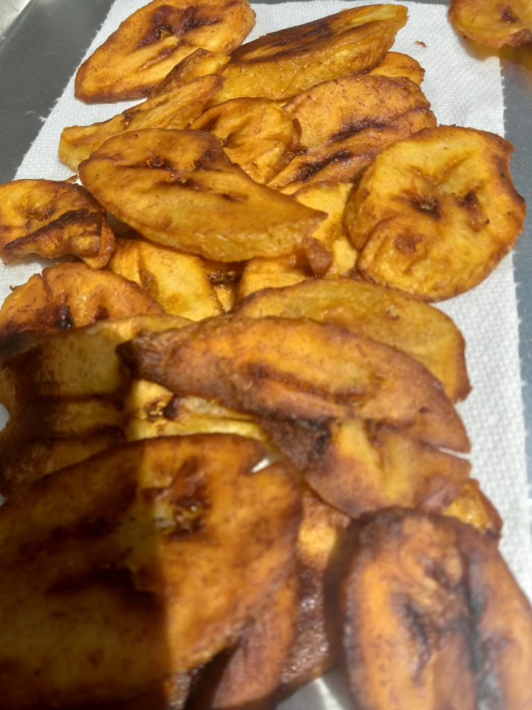 CLOSE UP OF FRIED PLANTAINS ON A SMALL BAKING TRAY LINED WITH A PAPER TOWEL