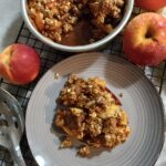 picture of apple walnut crisp with three apples in the background