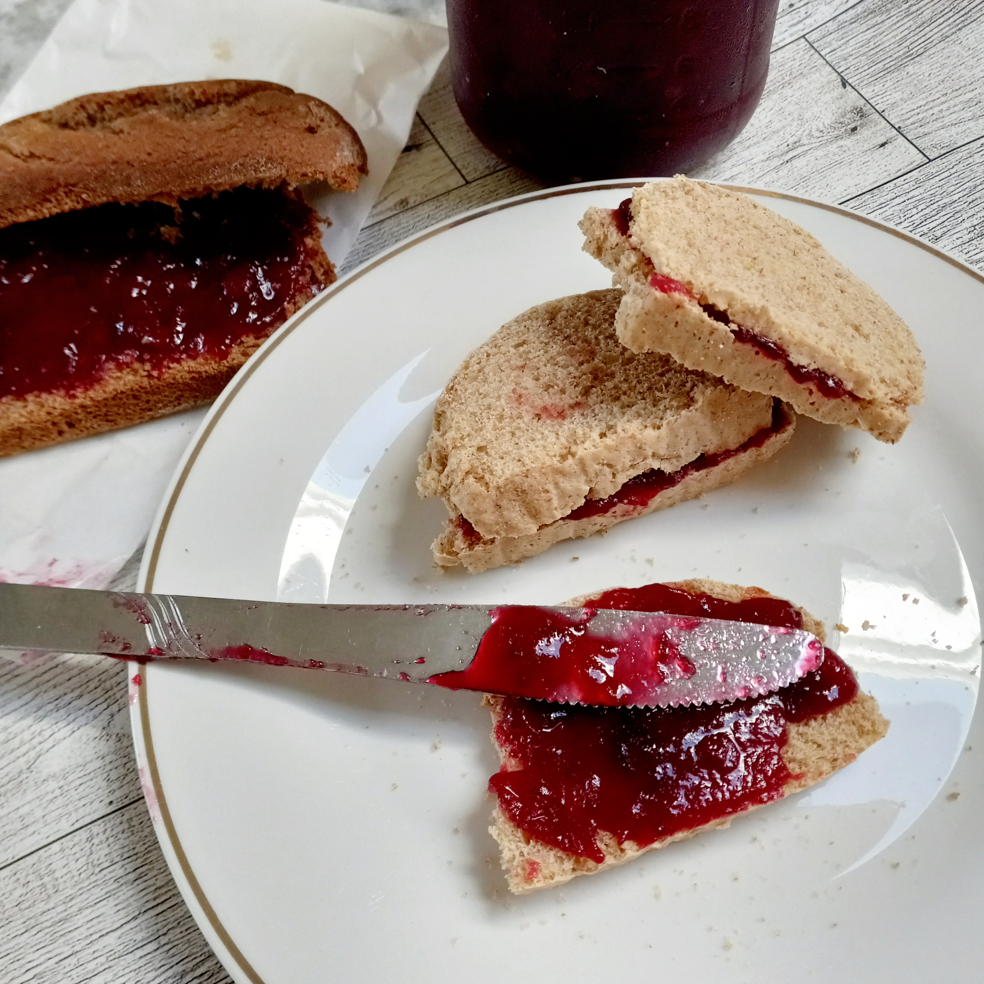 cranberry cinnamon jam sandwiches with jar of jam and a banana bread in the background