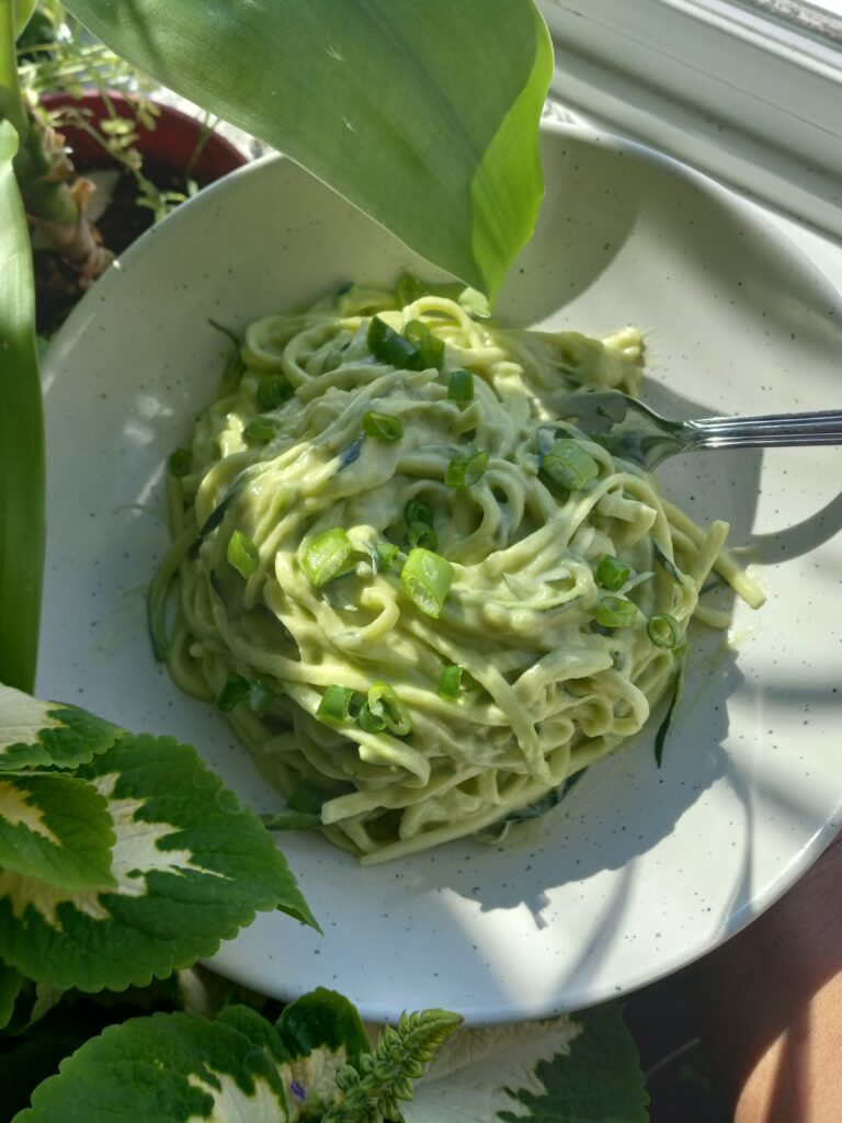 a plate of zucchini noodles in a avocado and tahini sauce