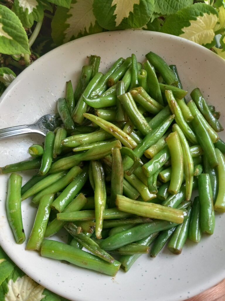 plates of coconut oil green beans with garlic with a fork on the side