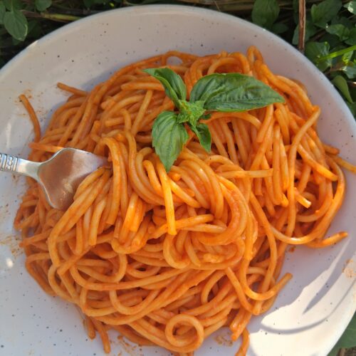 A plate of Roasted Red Pepper Pasta with a fork twirling a few strands of pasta.