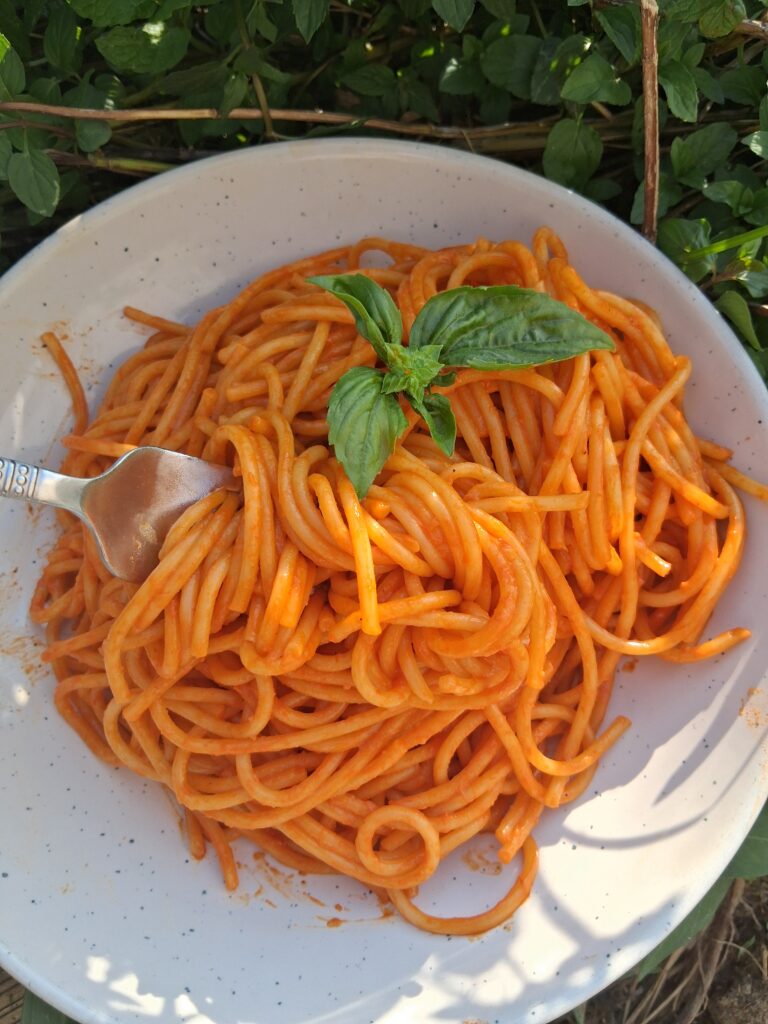 A plate of Roasted Red Pepper Pasta with a fork twirling a few strands of pasta.