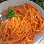 plate of roasted red pepper pasta with a fork twirling a few strands of spagetti.