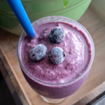 a glass of blueberry breakfast smoothie with 3 blueberrie son top