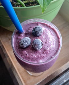 a glass of blueberry breakfast smoothie with 3 blueberrie son top
