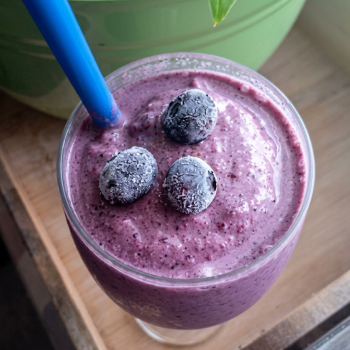 a glass of blueberry breakfast smoothie with 3 blueberrie son top